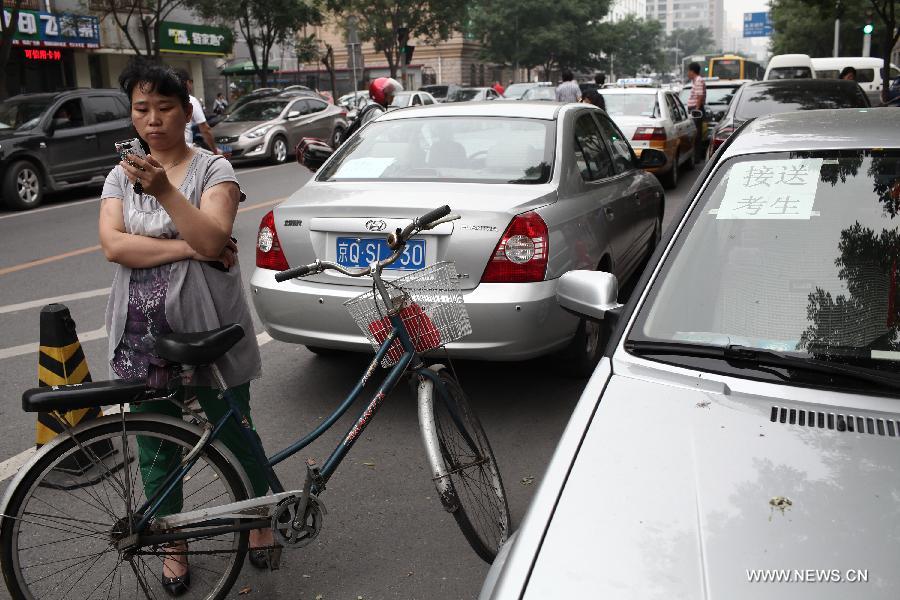 A woman waits for her child taking the 2013 senior high school entrance examination in the No. 31 Middle School in Beijing, capital of China, June 24, 2013. About 88,000 middle school students participated in the three-day examination which lasts from June 24 to June 26 in Beijing. (Xinhua/Jin Liwang) 