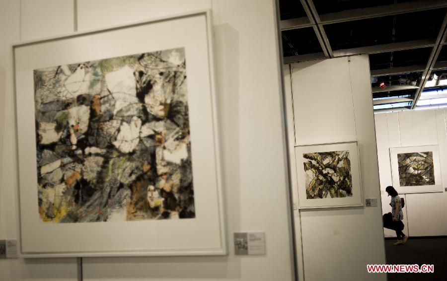 A visitor watches the exhibited paintings on a gallery show in Hong Kong, south China, June, 24, 2013. A gallery show exhibition of the paintings created by artist Xiao Jiahong opened here on Monday. (Xinhua/Lui Siu Wai) 