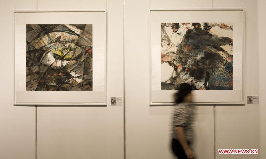 A visitor walks past the exhibited paintings on a gallery show in Hong Kong, south China, June, 24, 2013. A gallery show exhibition of the paintings created by artist Xiao Jiahong opened here on Monday. (Xinhua/Lui Siu Wai)