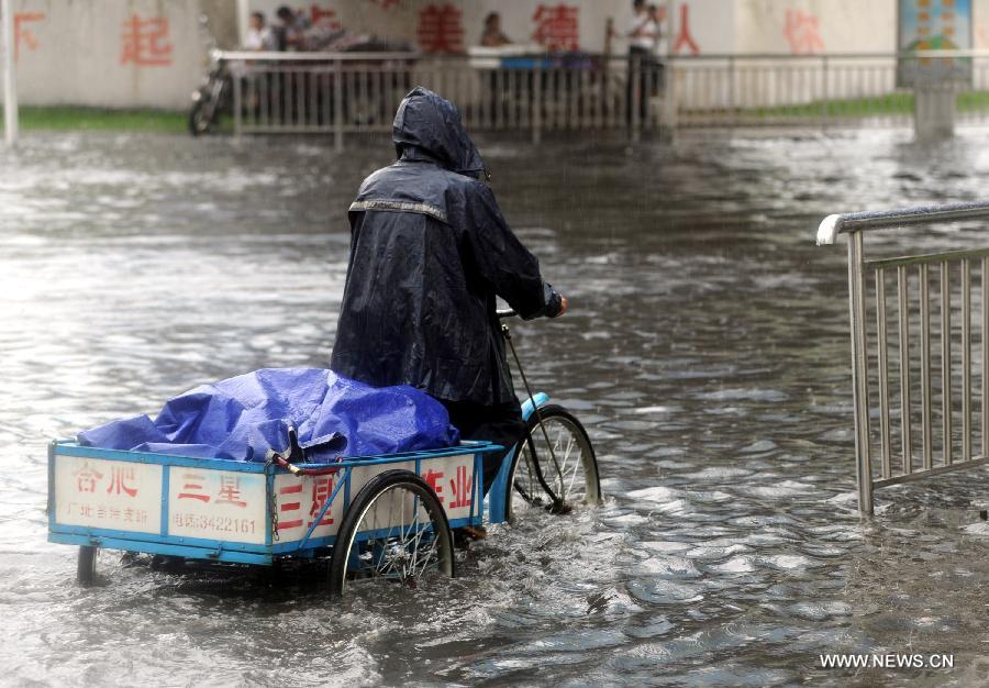 A man rides a tricycle on a flooded street as heavy rainfall hit Tongling of east China's Anhui Province, June 24, 2013. (Xinhua/Guo Shining) 
