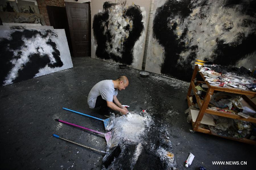 Zhang Fangbai, a 51-year-old painter, mixes the paint at his studio in Beijing, capital of China, June 19, 2013. Zhang has specialized in painting eagles for a dozen of years. (Xinhua/Wu Xiaochu) 