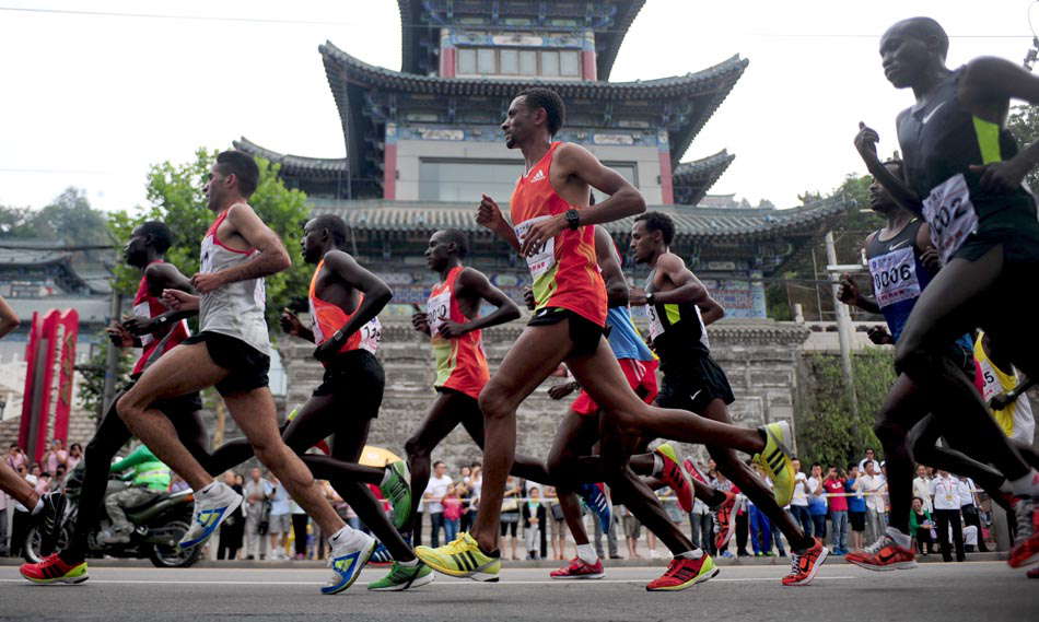 A group of runners pass the ancient buildings in Lanzhou, northwest China’s Gansu province on June 15, 2013. The 2013 Lanzhou International Marathon with the highest altitude route attracted 43,600 competitors from 26 countries and regions all around the world. (Photo by Zhang Meng/ Xinhua)