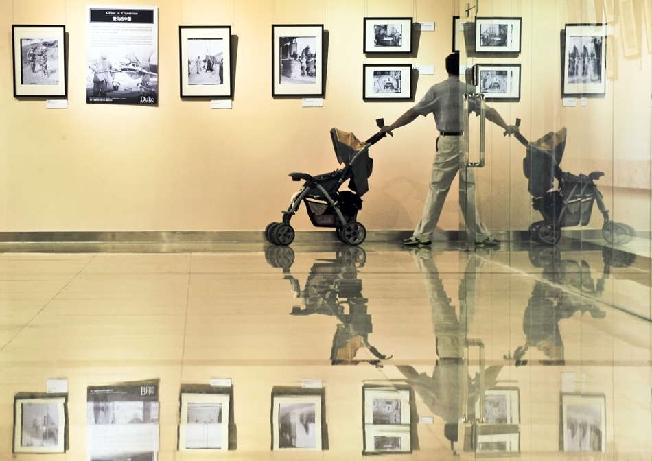 A man views the photos in the exhibition about the old Beijing 100 years ago on June 18, 2013. The exhibition presents over 100 photos taken by American sociologist Sidney Gamble from 1908 to 1931 as a part of the serial exhibition of Capital Library. The photos reflected lifestyle, folk custom and architecture in old Beijing. (Photo by Wang Jingsheng/ Xinhua)