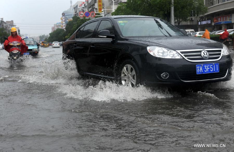 A car moves on the waterlogged road in Yangzhou City, east China's Jiangsu Province, June 25, 2013. Heavy rainfall hit many parts of Jiangsu on Tuesday. (Xinhua)