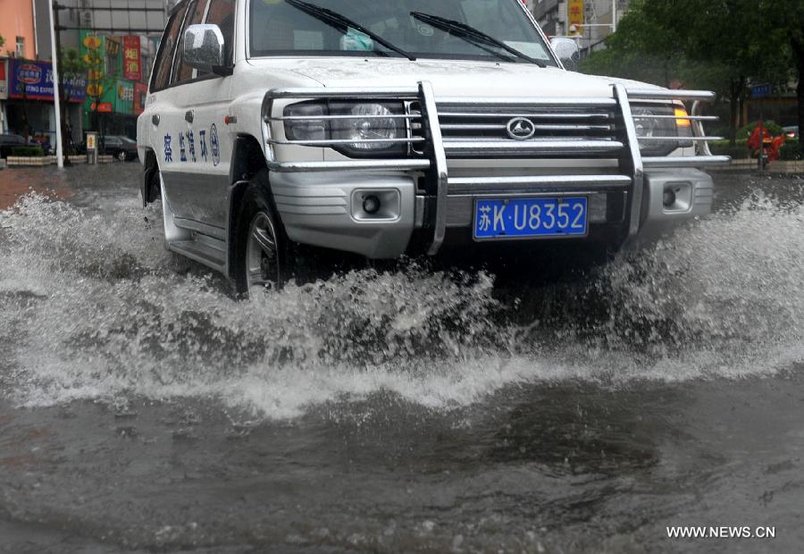 A car moves on the waterlogged road in Yangzhou City, east China's Jiangsu Province, June 25, 2013. Heavy rainfall hit many parts of Jiangsu on Tuesday. (Xinhua)