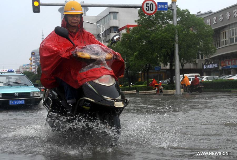 A citizen rides on the waterlogged road in Yangzhou City, east China's Jiangsu Province, June 25, 2013. Heavy rainfall hit many parts of Jiangsu on Tuesday. (Xinhua/Yang Yue)