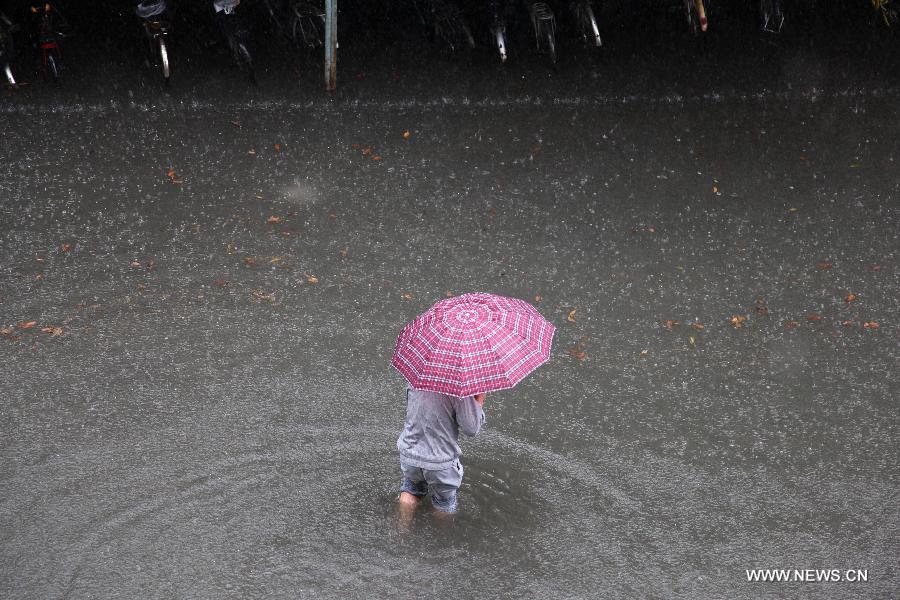 Citizens walk on the waterlogged road in Nanjing City, capital of east China's Jiangsu Province, June 25, 2013. Heavy rainfall hit many parts of Jiangsu on Tuesday. (Xinhua)