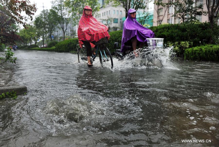 Citizens ride on the waterlogged road in Yangzhou City, east China's Jiangsu Province, June 25, 2013. Heavy rainfall hit many parts of Jiangsu on Tuesday. (Xinhua/Yang Yue)