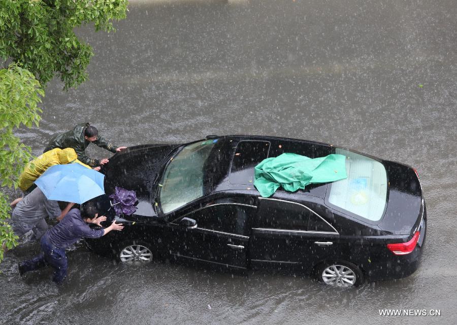 Citizens push a car on a waterlogged road in Nanjing City, capital of east China's Jiangsu Province, June 25, 2013. Heavy rainfall hit many parts of Jiangsu on Tuesday. (Xinhua)