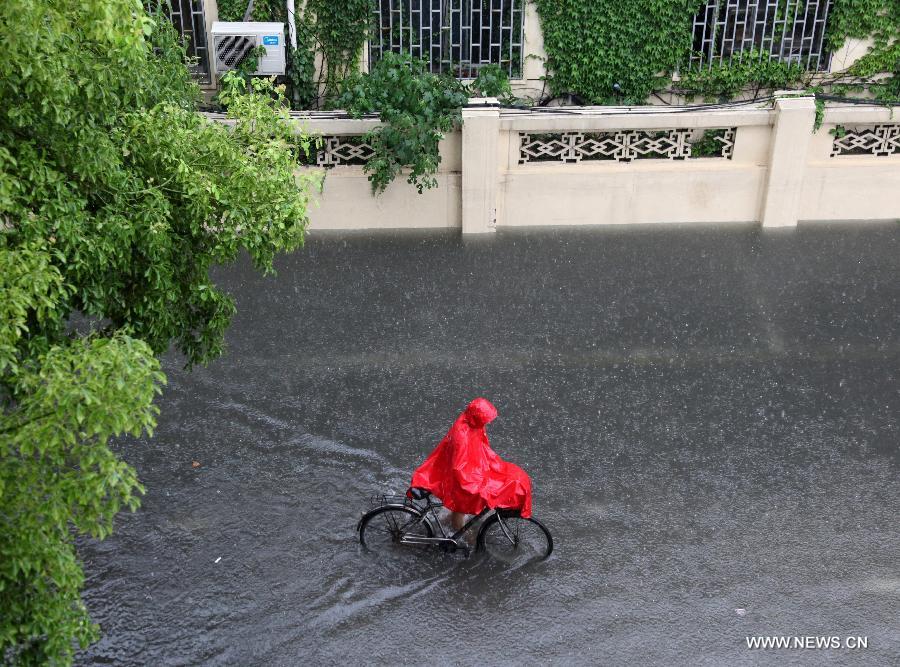 A citizen rides on the waterlogged road in Nanjing City, capital of east China's Jiangsu Province, June 25, 2013. Heavy rainfall hit many parts of Jiangsu on Tuesday. (Xinhua)