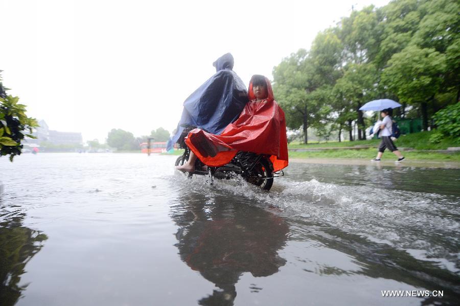 Citizens ride in the rain on the waterlogged road in Yangzhou City, east China's Jiangsu Province, June 25, 2013. Heavy rainfall hit many parts of Jiangsu on Tuesday. (Xinhua/Meng Delong)