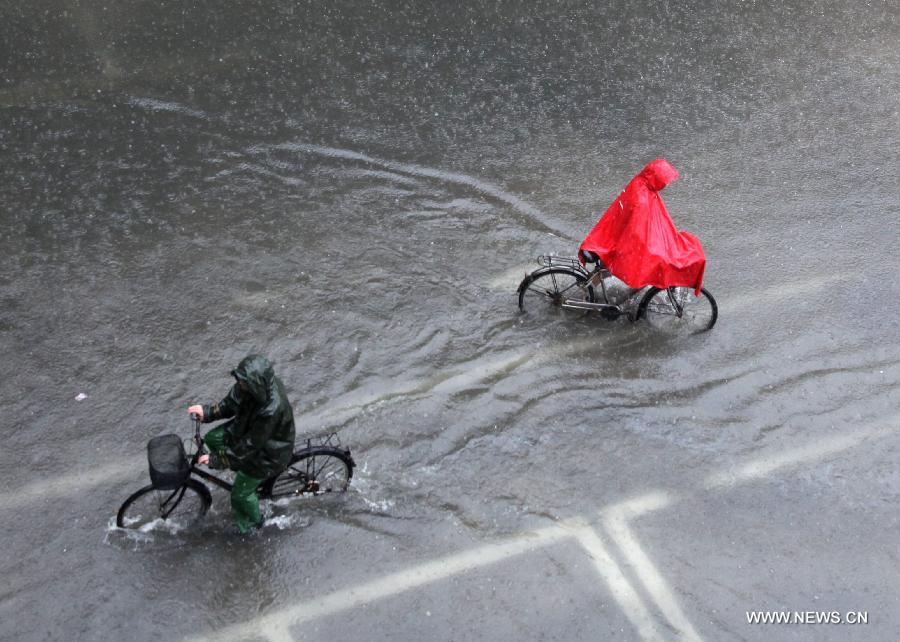 Citizens ride on the waterlogged road in Nanjing City, capital of east China's Jiangsu Province, June 25, 2013. Heavy rainfall hit many parts of Jiangsu on Tuesday. (Xinhua)