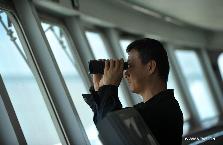 Captain of the "Xinhai No. 19" ro-ro passenger ship which ferries along the Qiongzhou Strait observes navigation on the Strait in south China's Hainan Province, June 25, 2013. June 25 marks the third International Day of the Seafarer. (Xinhua/Zhao Yingquan) 