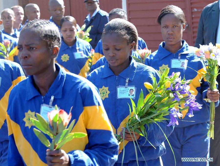 Police officers present flowers to former South African president Nelson Mandela outside the hospital where Mandela is treated in Pretoria, South Africa, on June 25, 2013. South Africans on Monday were holding their breath over former President Nelson Mandela's health that has deteriorated from serious to critical. Mandela, 94, has been hospitalized for a recurring lung problem since June 8. (Xinhua/Li Qihua)