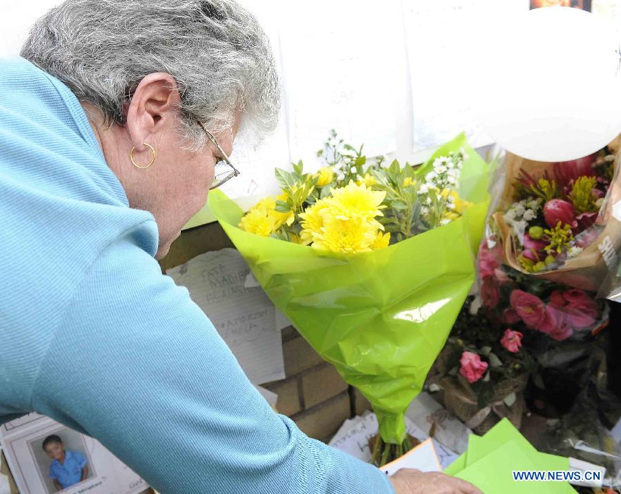 A woman presents flowers to former South African president Nelson Mandela outside the hospital where Mandela is treated in Pretoria, South Africa, on June 25, 2013. South Africans on Monday were holding their breath over former President Nelson Mandela's health that has deteriorated from serious to critical. Mandela, 94, has been hospitalized for a recurring lung problem since June 8. (Xinhua/Li Qihua)