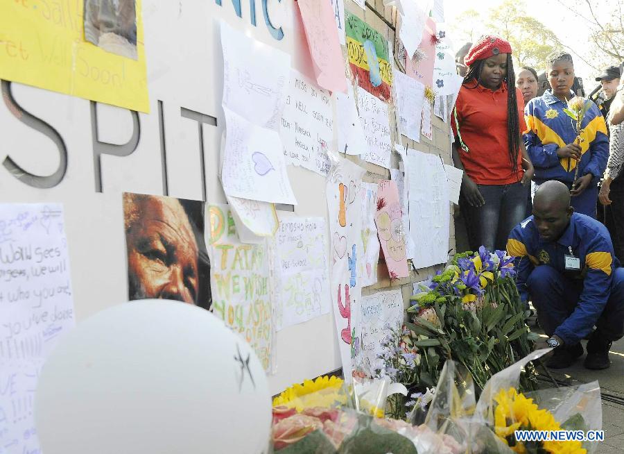 Police officers present flowers to former South African president Nelson Mandela outside the hospital where Mandela is treated in Pretoria, South Africa, on June 25, 2013. South Africans on Monday were holding their breath over former President Nelson Mandela's health that has deteriorated from serious to critical. Mandela, 94, has been hospitalized for a recurring lung problem since June 8. (Xinhua/Li Qihua)