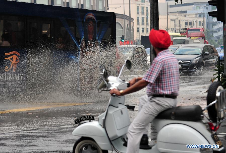 A bus splashes water while crossing a puddle from the rain in Singapore, on June 25, 2013. A sudden downpour relieved the smoke haze caused by forest fires in neighboring Indonesia in Singapore on Tuesday afternoon. (Xinhua/Then Chih Wey)