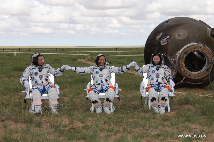 Astronauts Zhang Xiaoguang, Nie Haisheng and Wang Yaping (from left to right) shake hands after they got out of the re-entry capsule of China's Shenzhou-10 spacecraft following its successful landing at the main landing site in north China's Inner Mongolia Autonomous Region on June 26, 2013. (Xinhua/Wang Jianmin)