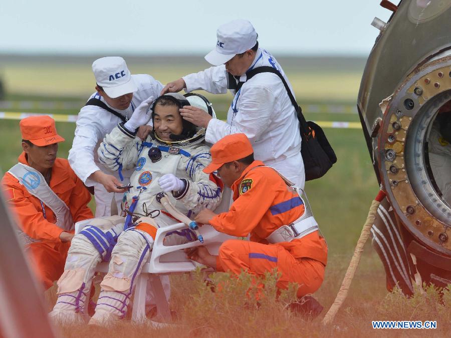 Astronaut Zhang Xiaoguang salutes after going out of the re-entry capsule of China's Shenzhou-10 spacecraft following its successful landing at the main landing site in north China's Inner Mongolia Autonomous Region on June 26, 2013. (Xinhua/Ren Junchuan) 