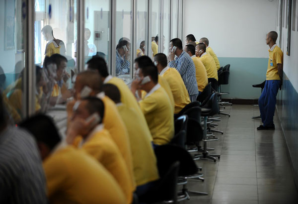 Youngsters recovering from drug addiction talk to their relatives by phone through a glass screen at a rehab center in Shanxi, June 13, 2013. [Photo/Xinhua]