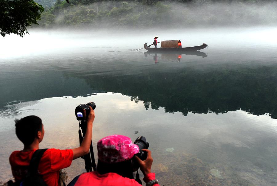 Tourists take photos of a boat on the fog-enveloped Xiaodongjiang River in Zixing City of central China's Hunan Province, June 25, 2013. (Xinhua/Chen Haining) 