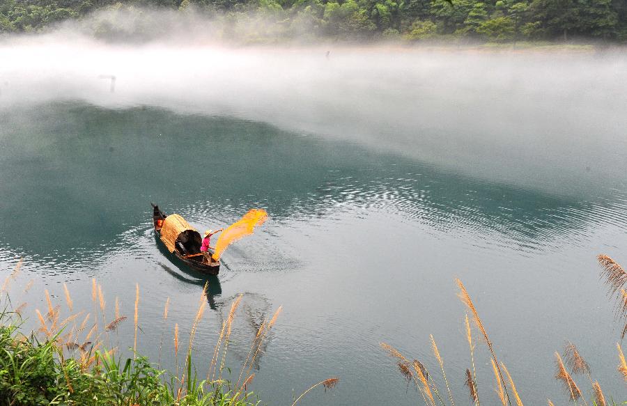 A fisherman casts a net on the fog-enveloped Xiaodongjiang River in Zixing City of central China's Hunan Province, June 25, 2013. (Xinhua/Chen Haining) 