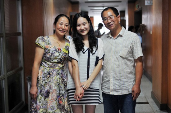 Zhang Yi is the top scorer in humanities in the National College Entrance Examination in Chongqing, with total score 685. Picture shows her parents and her.(Photo/GMW.cn)