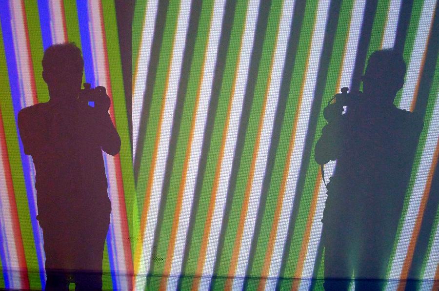 A visitor takes photo of artworks during the exhibition of the Venezuelan artist Carlos Cruz-Diez "Circumstance and Ambiguity of Color" in Hangzhou, capital of east China's Zhejiang Province, June 27, 2013. The exhibition will last till July 23. (Xinhua/Shi Jianxue)  