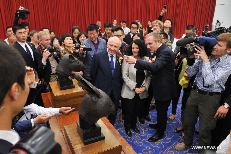 People look at two bronze animal head sculptures plundered by western invaders one-and-a-half centuries ago at a handover ceremony of the heads in Beijing, capital of China, June 28, 2013. The heads of a rat and a rabbit, parts of a fountain clock that previously stood at the Old Summer Palace, or "Yuanmingyuan" in Chinese, were donated on April 26, 2013 by the Pinault family, which owns the French luxury brand Kering. The handover ceremony was held Friday at National Museum of China. (Xinhua/Li Xin) 