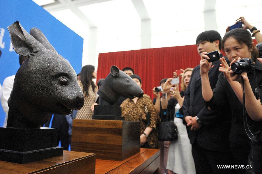 People take pictures of two bronze animal head sculptures plundered by western invaders one-and-a-half centuries ago during a handover ceremony of the heads in Beijing, capital of China, June 28, 2013. The heads of a rat and a rabbit, parts of a fountain clock that previously stood at the Old Summer Palace, or "Yuanmingyuan" in Chinese, were donated on April 26, 2013 by the Pinault family, which owns the French luxury brand Kering. The handover ceremony was held Friday at National Museum of China. (Xinhua/Li Xin)