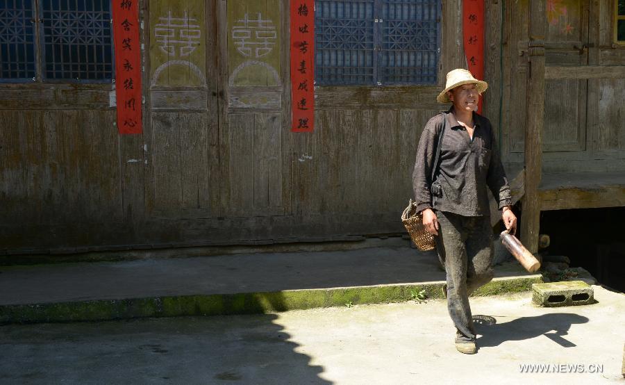 A villager named Zhang Xin'an goes to work at Jinlongba Village in Enshi City, central China's Hubei Province, June 27, 2013. The Jinlongba Village was listed among the 646 Chinese Traditional Villages in 2012 and villagers here followed the traditional way of living. (Xinhua/Yang Shunpi)  