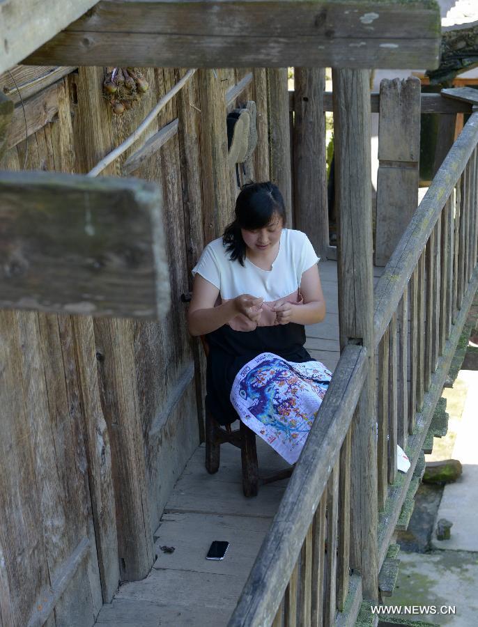 A girl named Zhang Er makes a cross-stitch at Jinlongba Village in Enshi City, central China's Hubei Province, June 27, 2013. The Jinlongba Village was listed among the 646 Chinese Traditional Villages in 2012 and villagers here followed the traditional way of living. (Xinhua/Yang Shunpi)  