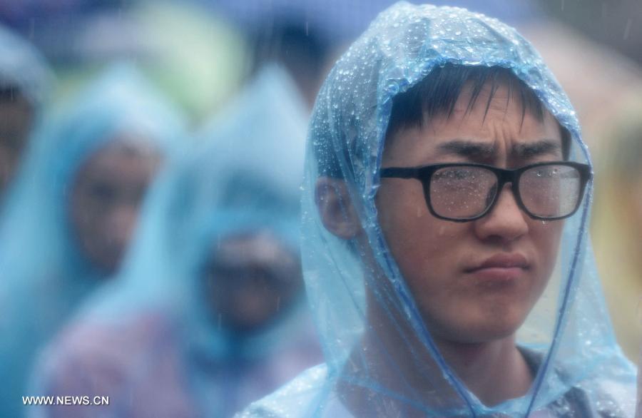 Graduates attend the graduation ceremony of Zhejiang University in the rain in Hangzhou, capital of east China's Zhejiang Province, June 29, 2013. The graduation ceremony was held here Saturday. (Xinhua/Han Chuanhao)