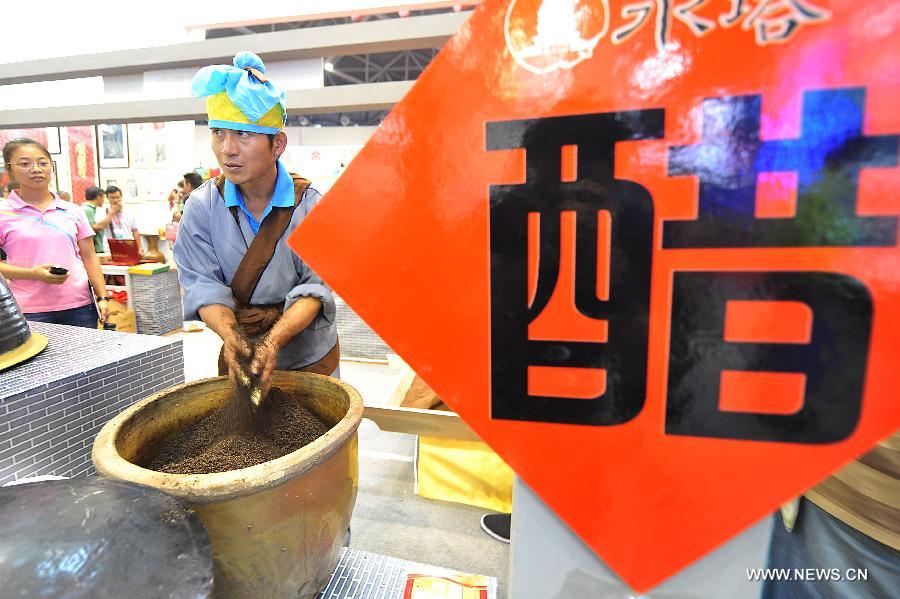 A staff member demonstrates the technique of producing local vinegar during the 1st Shanxi Cultural Industry Expo in Taiyuan, capital of north China's Shanxi Province, June 29, 2013. The exhibition will last till July 3. (Xinhua/Zhan Yan) 