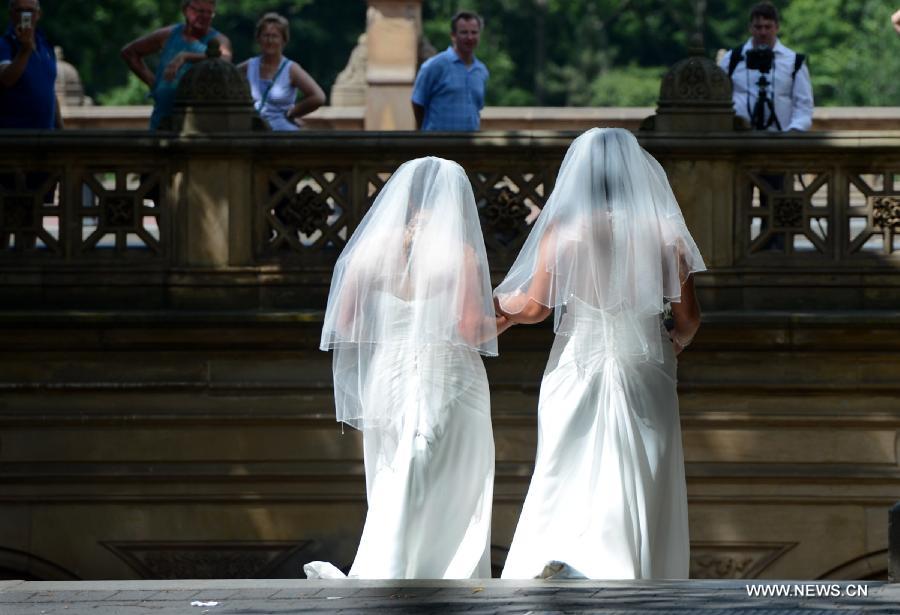 A homosexual couple in wedding dresses pose for photos at the Central Park in New York City, June 28, 2013. U.S. Supreme Court on Wednesday issued a pair of rulings expanding homosexuals' right to marry, striking down Defense of the Marriage Act (DOMA), which bans same-sex married couples from receiving federal benefits, while declining to rule on another case concerning California's ban on same-sex marriage, opening the door for the state to legalize gay marriage. (Xinhua/Wang Lei) 