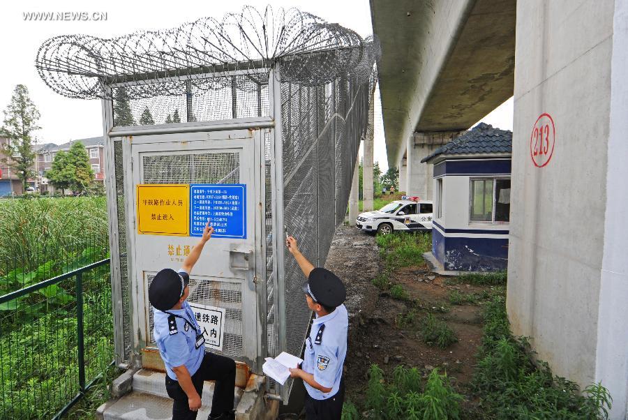 Policemen check the emergency channel for a high-speed railway at the Deqing Station in east China's Zhejiang Province, June 29, 2013. A new high-speed railway that stretches across east China's Yangtze River Delta is scheduled to go into commercial service on July 1. The Nanjing-Hangzhou-Ningbo high-speed railway, with a designated top speed of 350 km per hour, will cut travel time between Nanjing, capital of east China's Jiangsu Province, and the port city of Ningbo in east China's Zhejiang Province to about two hours. High-speed trains will run at a speed of 300 km per hour during the initial operation period. (Xinhua/Tan Jin)