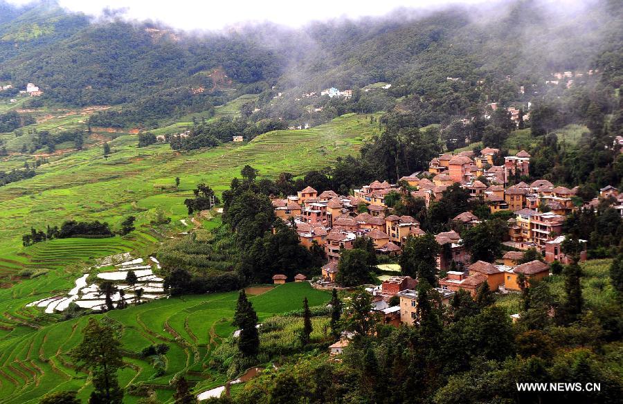 Photo taken on June 28, 2013 shows the village buildings and terraced fields in Yuanyang County of Honghe Prefecture in southwest China's Yunnan Province. The UNESCO's World Heritage Committee inscribed China's cultural landscape of Honghe Hani Rice Terraces onto the prestigious World Heritage List on June 22, bringing the total number of World Heritage Sites in China to 45. (Xinhua/Chen Haining) 