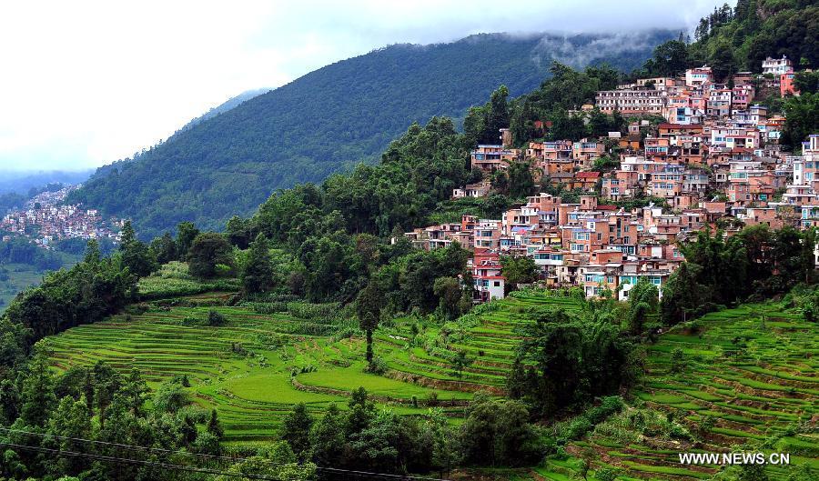 Photo taken on June 28, 2013 shows the village buildings and terraced fields in Yuanyang County of Honghe Prefecture in southwest China's Yunnan Province. The UNESCO's World Heritage Committee inscribed China's cultural landscape of Honghe Hani Rice Terraces onto the prestigious World Heritage List on June 22, bringing the total number of World Heritage Sites in China to 45. (Xinhua/Chen Haining) 