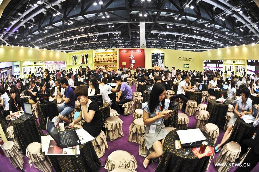 Visitors are seen at an exhibition booth at the wedding expo in Beijing, capital of China, June 28, 2013. The three-day 2013 China (summer) wedding expo kicked off here on Friday. Some 3,000 exhibitors from over 30 countries and regions participated in the exposition. (Xinhua/Wang Jingsheng) 