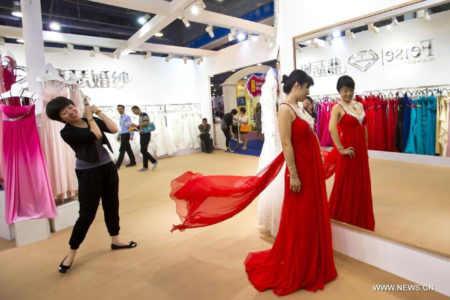 A bride-to-be (R) trys a suit of wedding robe at the wedding expo in Beijing, capital of China, June 28, 2013. The three-day 2013 China (summer) wedding expo kicked off here on Friday. Some 3,000 exhibitors from over 30 countries and regions participated in the exposition. (Xinhua/Zhao Bing) 