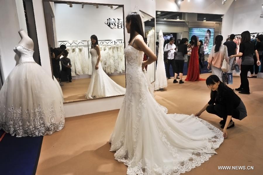 A woman trys a suit of wedding robe at the wedding expo in Beijing, capital of China, June 28, 2013. The three-day 2013 China (summer) wedding expo kicked off here on Friday. Some 3,000 exhibitors from over 30 countries and regions participated in the exposition. (Xinhua/Wang Jingsheng) 