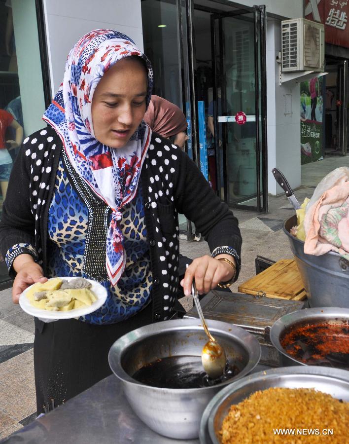 A vendor makes a local snack at the Id Kah Bazaar in the city of Hotan, northwest China's Xinjiang Uygur Autonomous Region, July 1, 2013. (Xinhua/Zhao Ge)