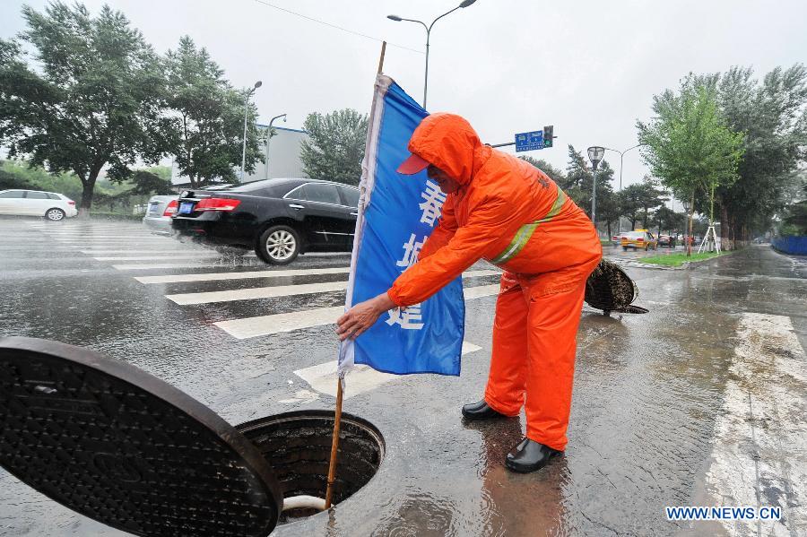 A municipal worker lifts the manhole cover to drain floods in Changchun, capital of northeast China's Jilin Province, July 2, 2013. Heavy rain has hit Jilin in recent days. (Xinhua/Zhang Nan)