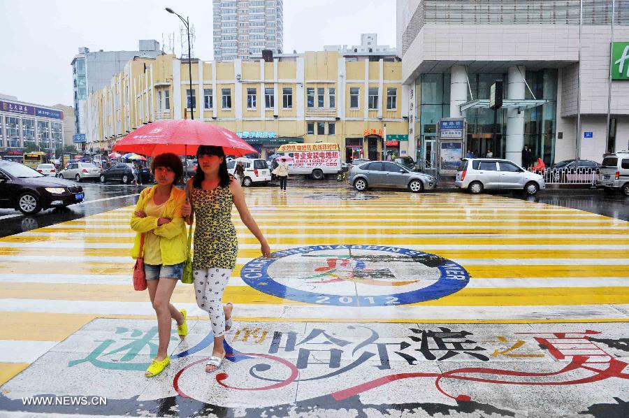 People walk on the pedestrian crosswalk in Harbin, capital of northeast China's Heilongjiang Province, July 2, 2013. The local meteorological center in Heilongjiang Province issued a blue rainstorm alert on Tuesday.(Xinhua/Wang Jianwei)