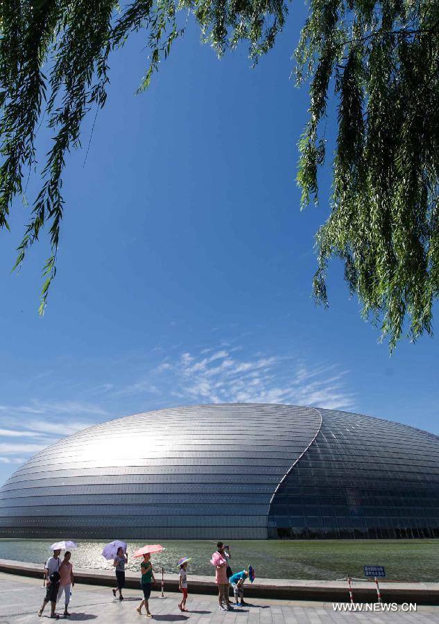 Tourists walk outside the National Centre for the Performing Arts in Beijing, capital of China, July 2, 2013. A rainstorm on Monday night brought Beijing with fine weather. (Xinhua/Luo Xiaoguang) 