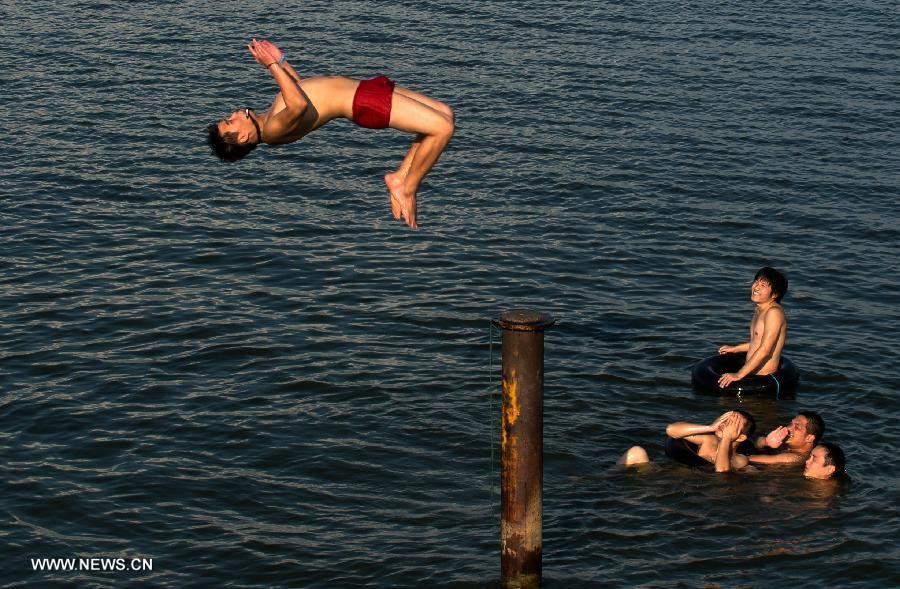 People enjoy coolness at the East Lake in Wuhan, capital of central China's Hubei Province, July 3, 2013. The highest temperature in Wuhan reached 36 degrees celsius on Wednesday. (Xinhua/Cheng Min)