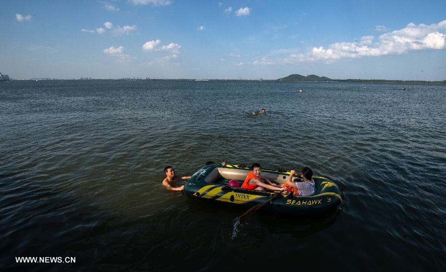 People enjoy coolness at the East Lake in Wuhan, capital of central China's Hubei Province, July 3, 2013. The highest temperature in Wuhan reached 36 degrees celsius on Wednesday. (Xinhua/Cheng Min)