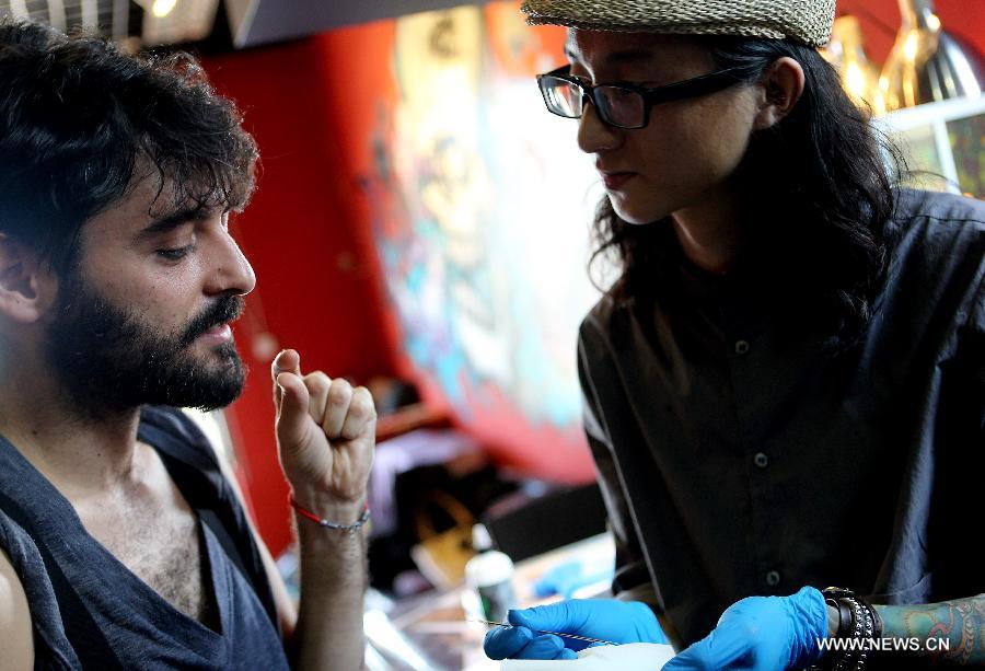 Juan Gonzalez Zamora (L) and Chen Gong discuss about the design of the tattoo in Beijing, capital of China, July 2, 2013. (Xinhua/Zhang Chuanqi)