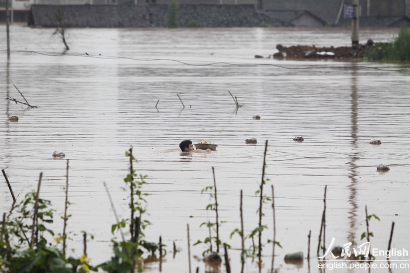 A man in Chongqing swam across a flooded river to fetch hot food for his pregnant wife trapped by rising floodwater.(Photo: CFP)