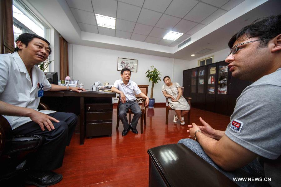 Mubeen Abdul (L), a student from Pakistan, talks with an alumna in a health clinic in Dongcun community in Nantong, east China's Jiangsu Province, June 28, 2013. Mubeen is a fresh graduate seeking for a job in Nantong from Nantong University, majoring in clinical medicine. He has rented a house and attended many job fairs in a month. No answer from employers and low income from part-time job exerted much pressure on him. Finally he got a job for reception of foreign guests and management in Nantong First People's Hospital on July 1, 2013. "I love China and I will continue studying for master's degree and qualification of medical practitioners," said Mubeen. (Xinhua/Huang Zhe)